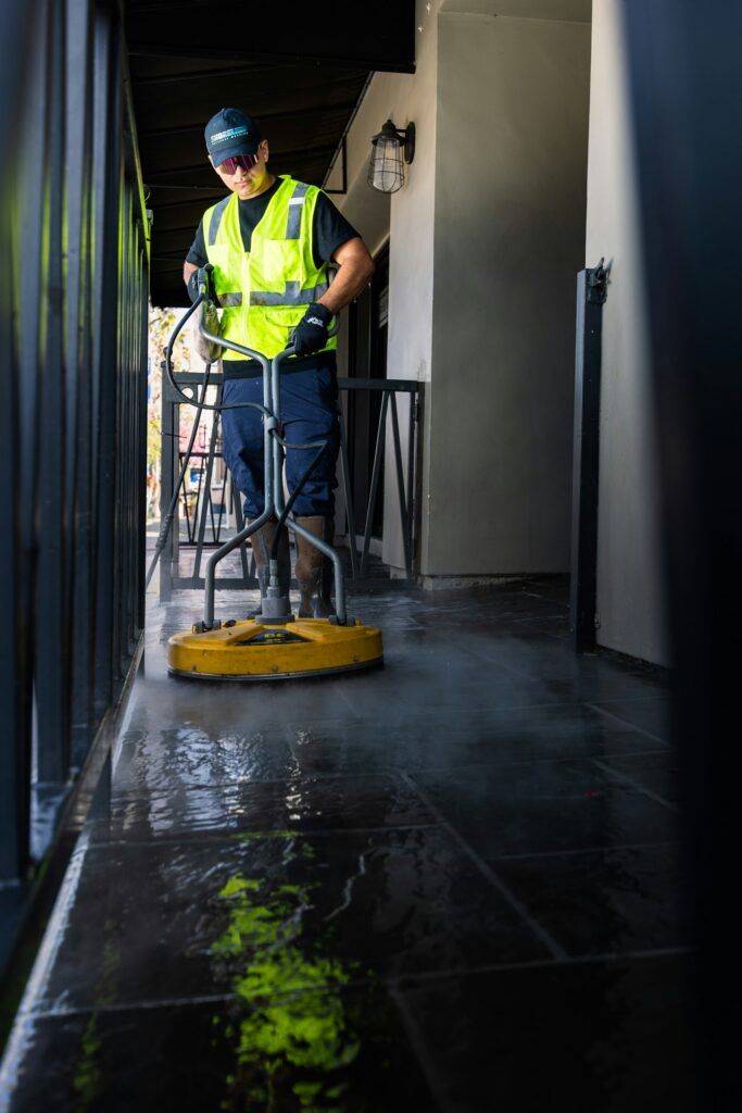 Cleaner in hi-vis using a floor scrubber